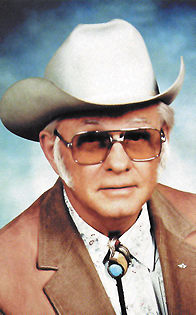 Thomas Carter looks like a character out of Dynasty with a ten gallon hat, bolo tie, mutton chops, and amber aviators